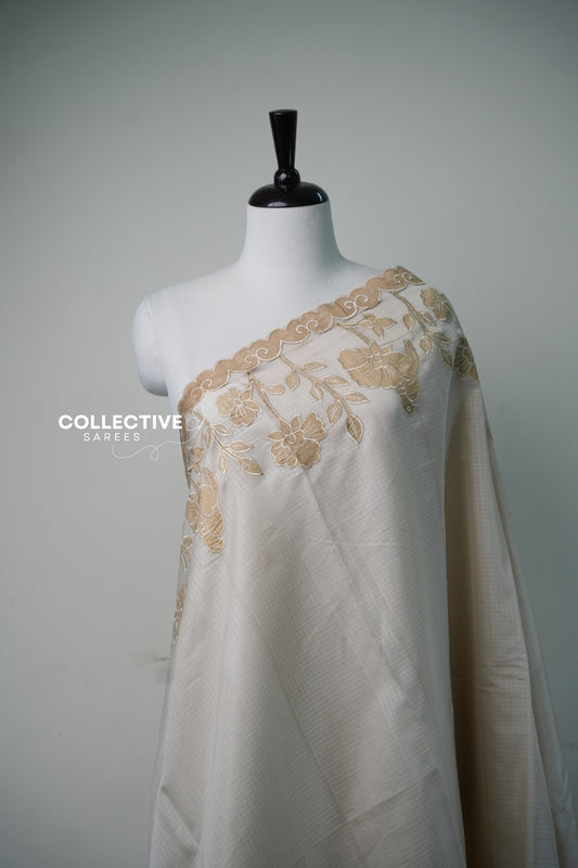 Close-up of beige appliqué floral work on cream kota saree