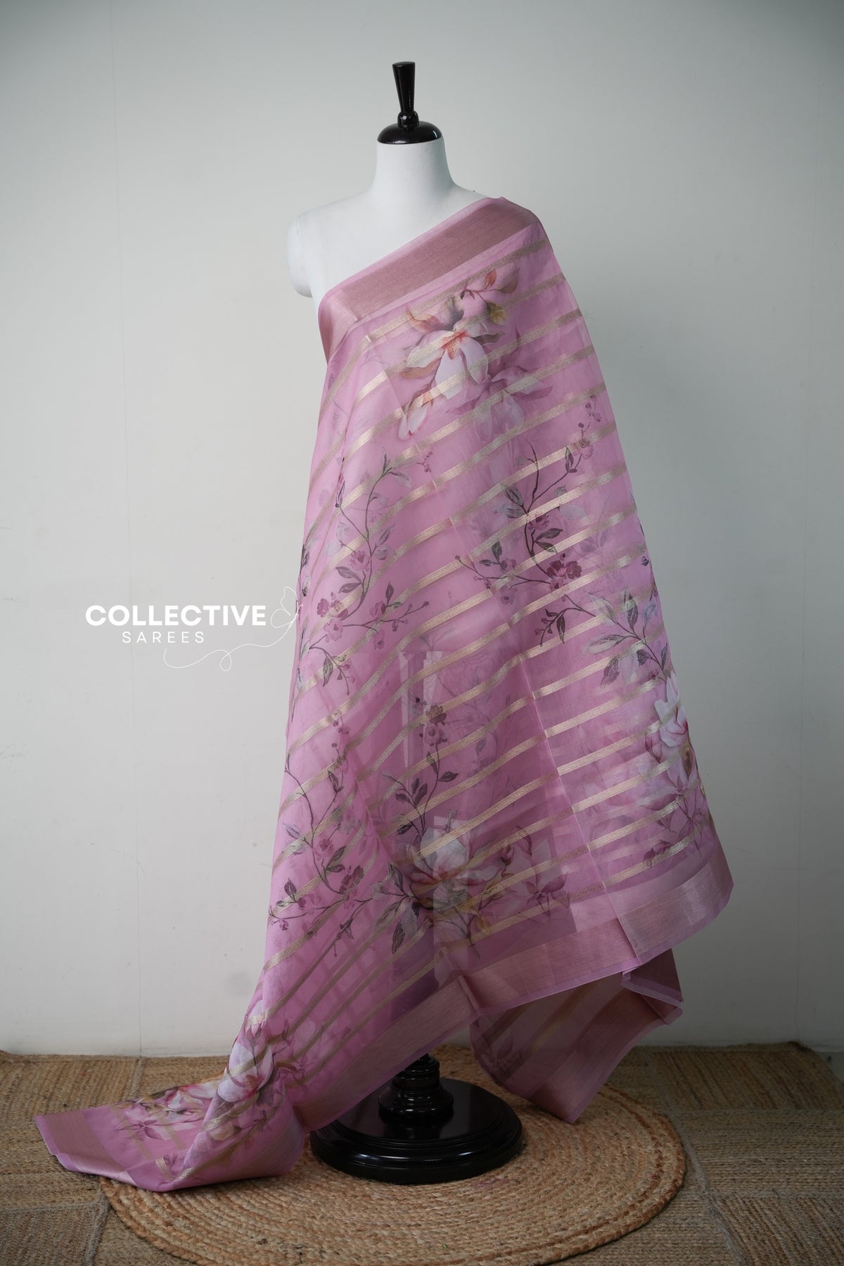 Pink organza saree with magnolia print and diagonal gold zari stripes, full drape
