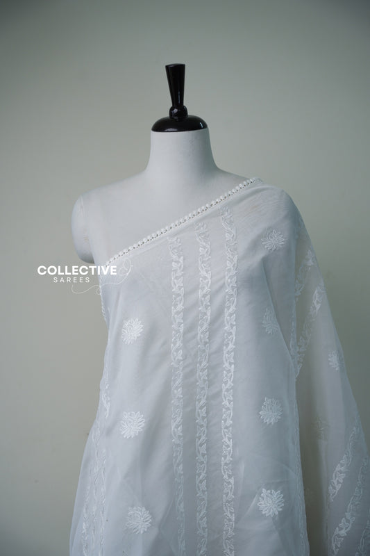Close-up of white thread vine embroidery, floral buttis and crochet lace edge on white organza saree
