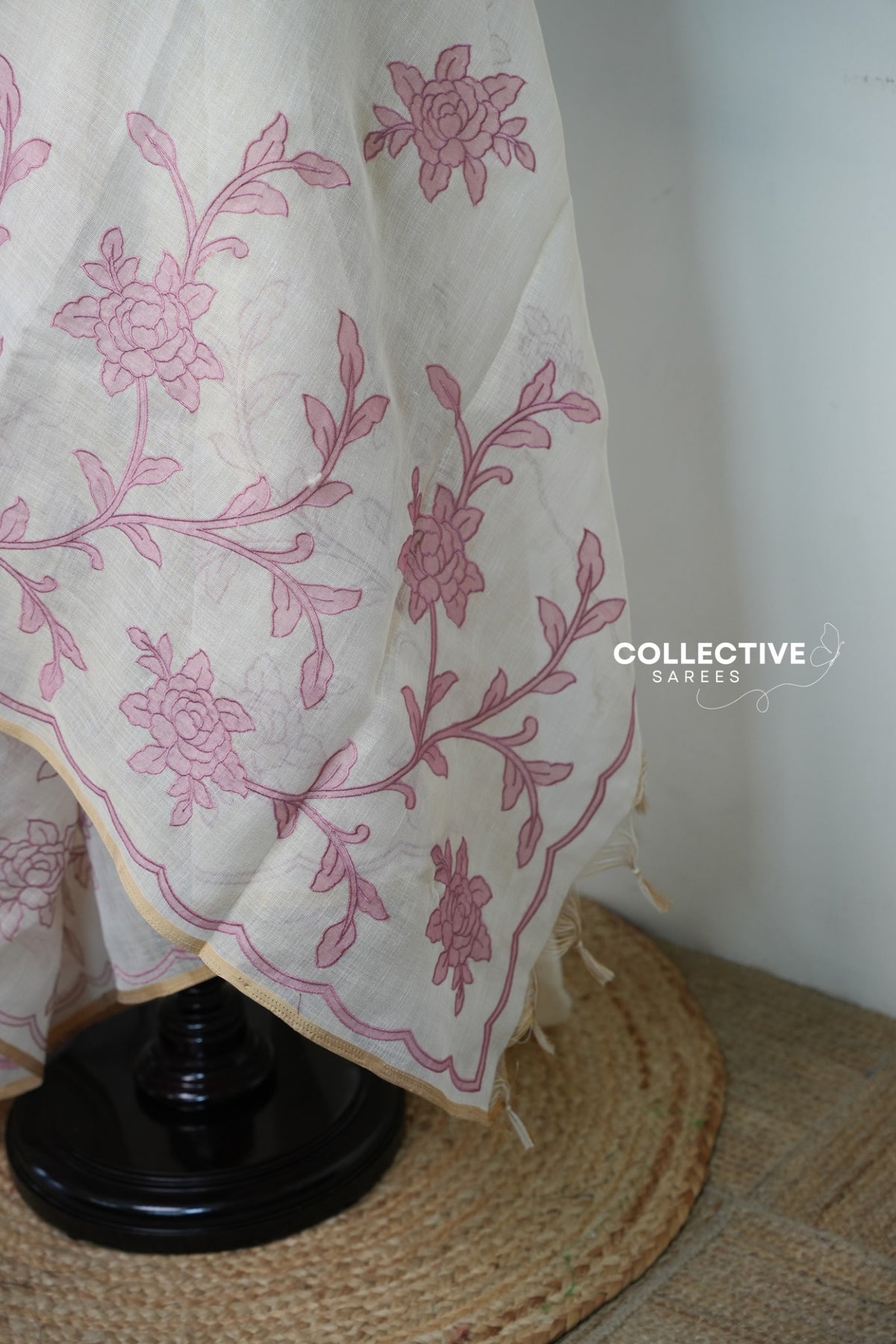 Beige soft tissue saree with pink floral appliqué work and gold-toned edging
