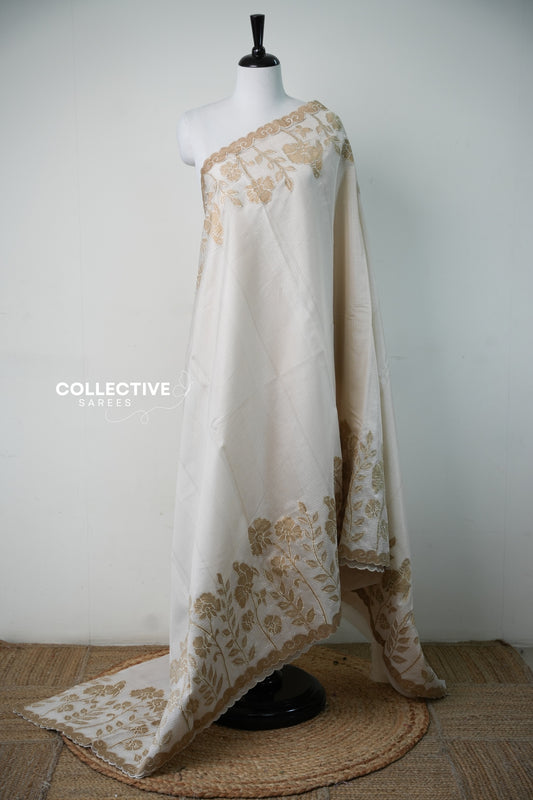 Cream silky kota saree with beige floral appliqué, full drape on mannequin