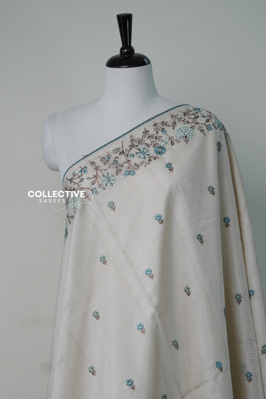 Cream kota saree embroidered floral vine border and teal buttis close-up