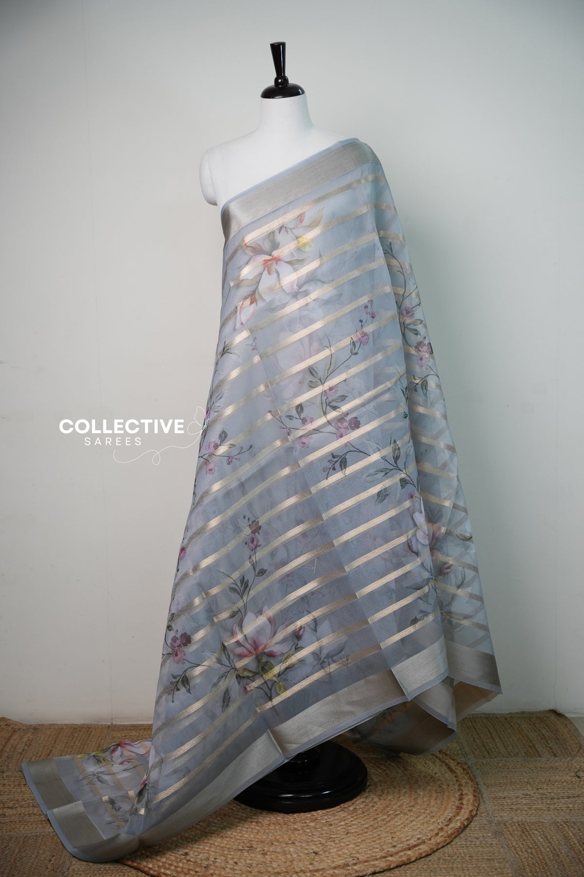 Ash organza saree with magnolia print and diagonal gold zari stripes, full drape