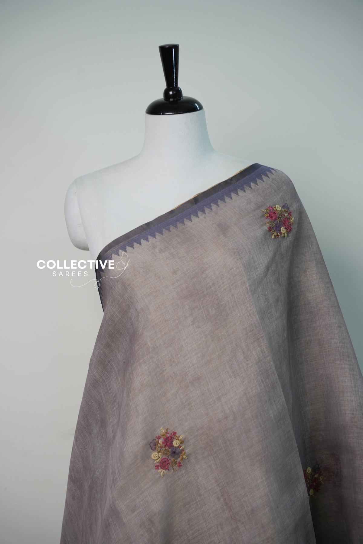 Light ash semi tissue saree with embroidered floral buttis and temple border close-up