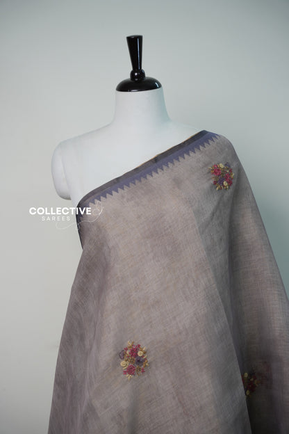 Light ash semi tissue saree with embroidered floral buttis and temple border close-up
