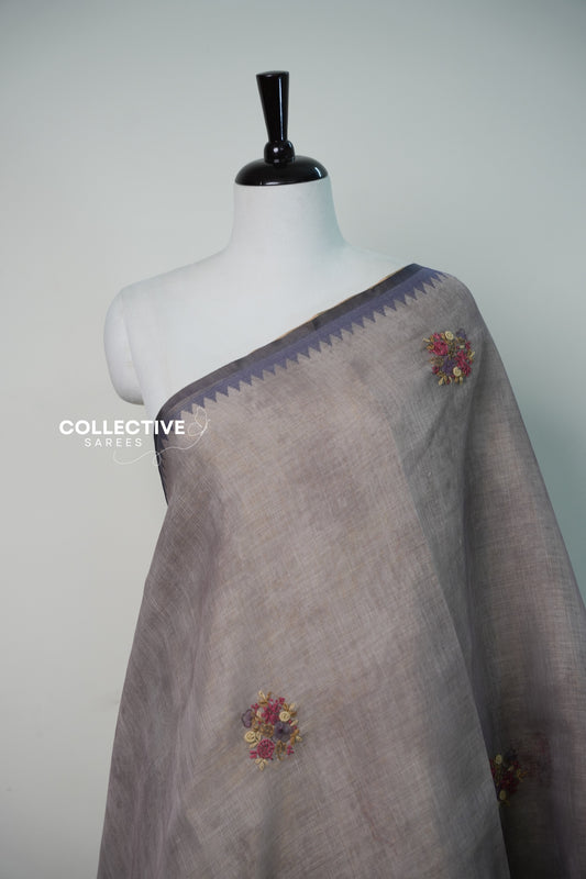 Light ash semi tissue saree with embroidered floral buttis and temple border close-up