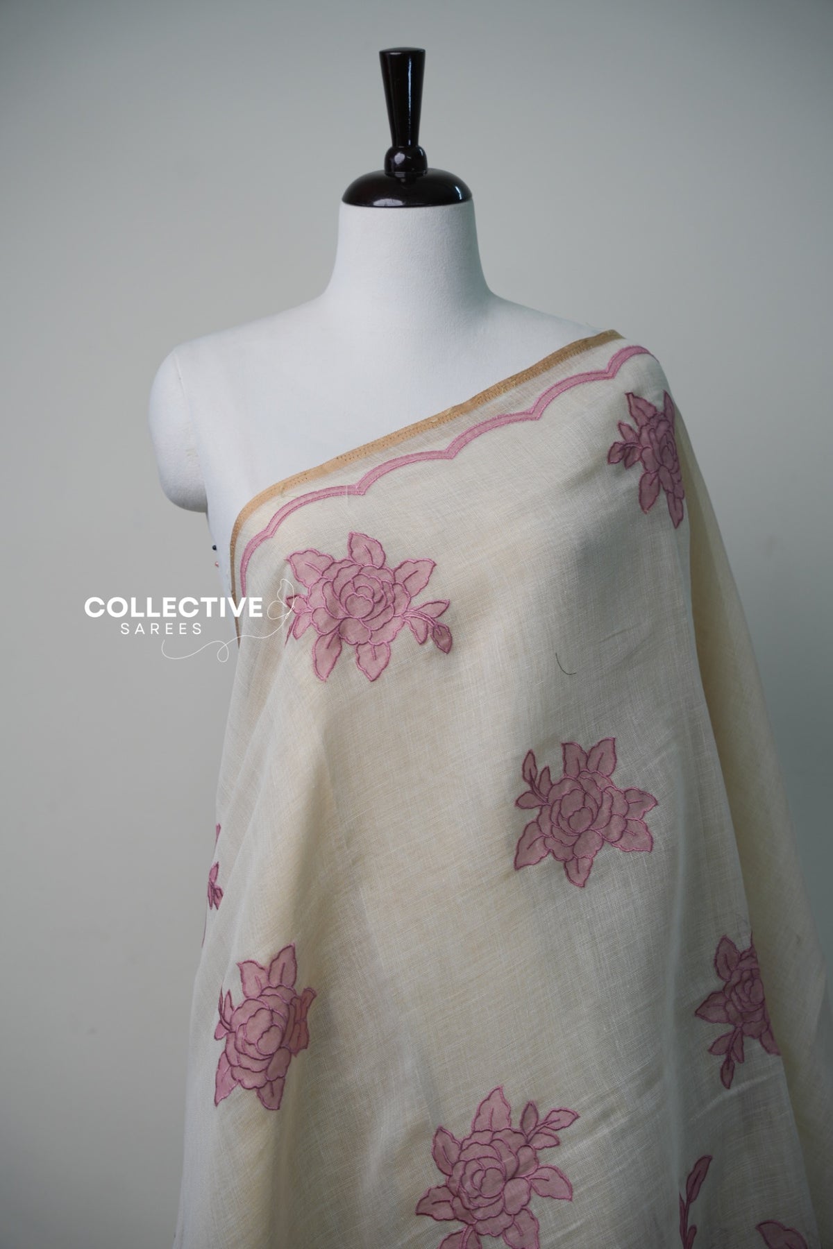 Beige soft tissue saree with pink floral appliqué work and gold-toned edging