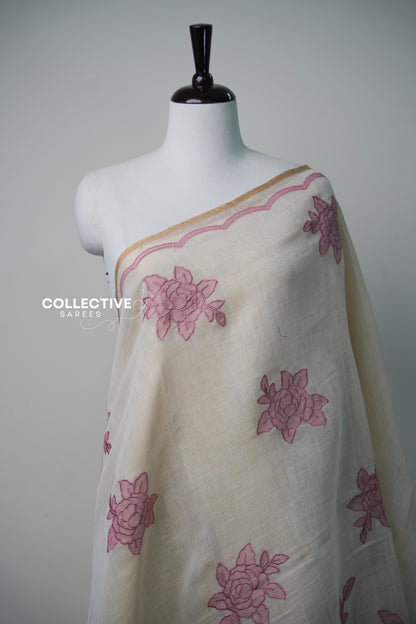 Beige soft tissue saree with pink floral appliqué work and gold-toned edging